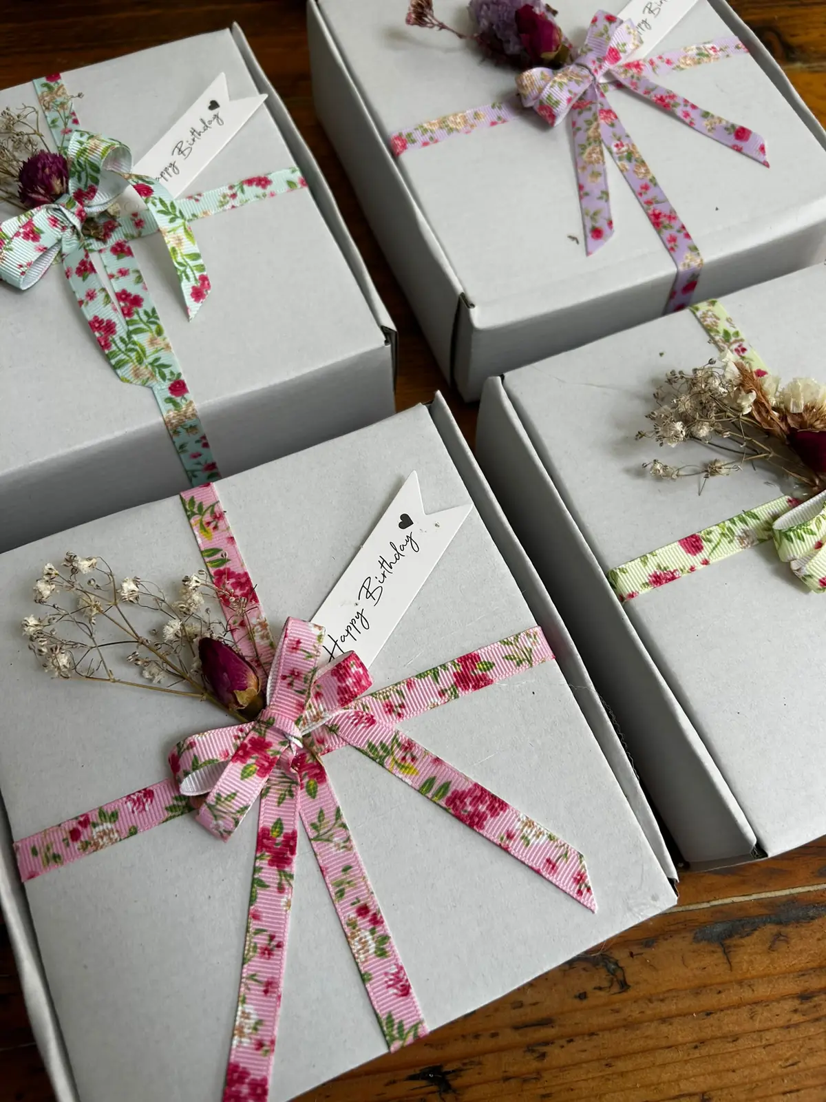 Gift boxes tied with floral ribbons, dried flowers and Happy Birthday tags