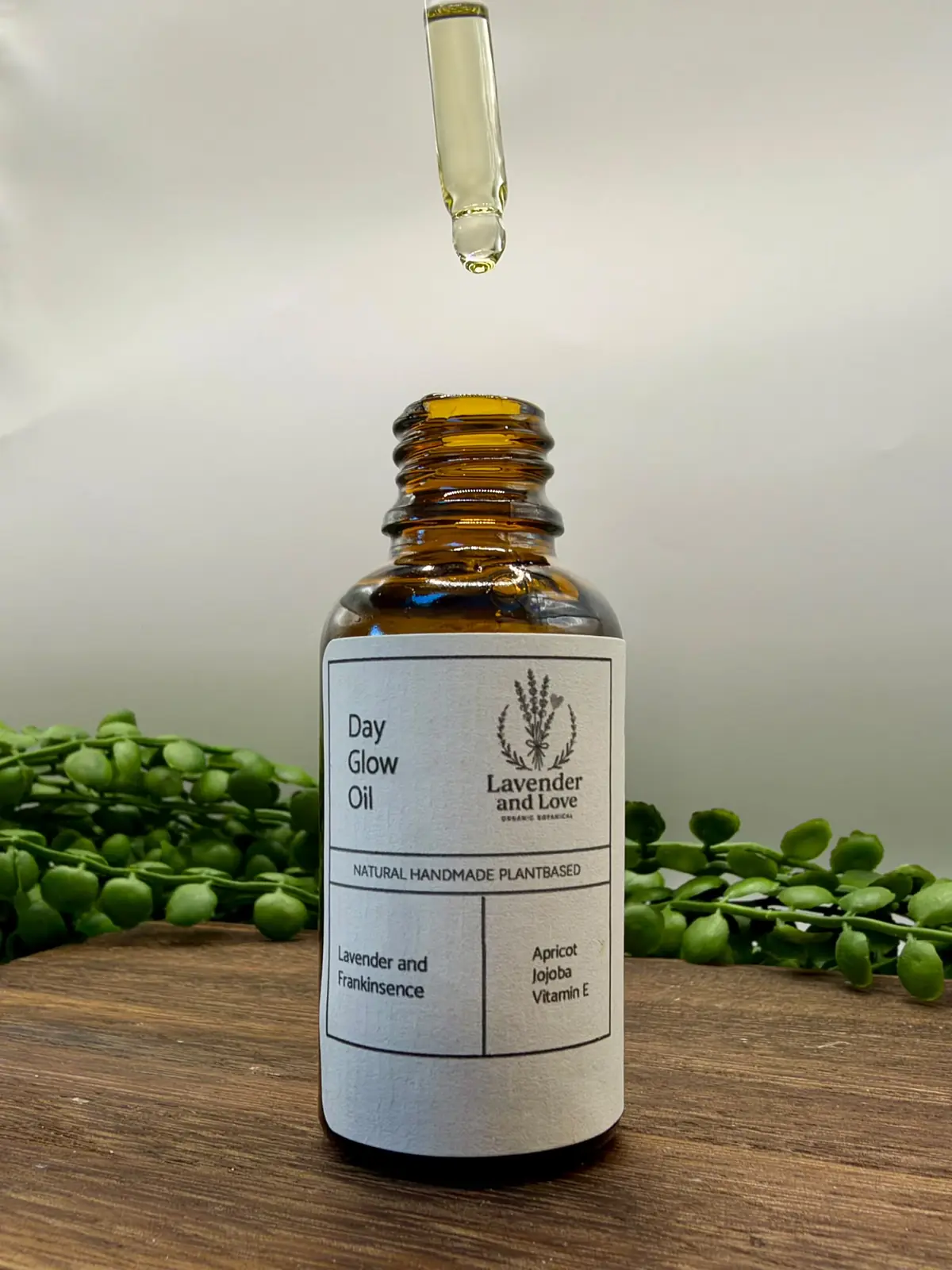 A dropper of Day Glow Oil held above its amber bottle