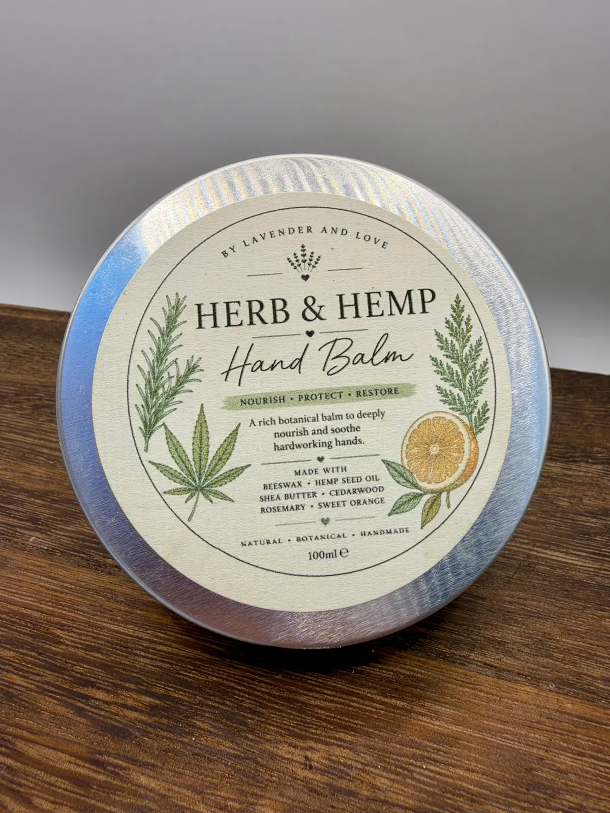 The illustrated lid of the Herb and Hemp Hand Balm tin