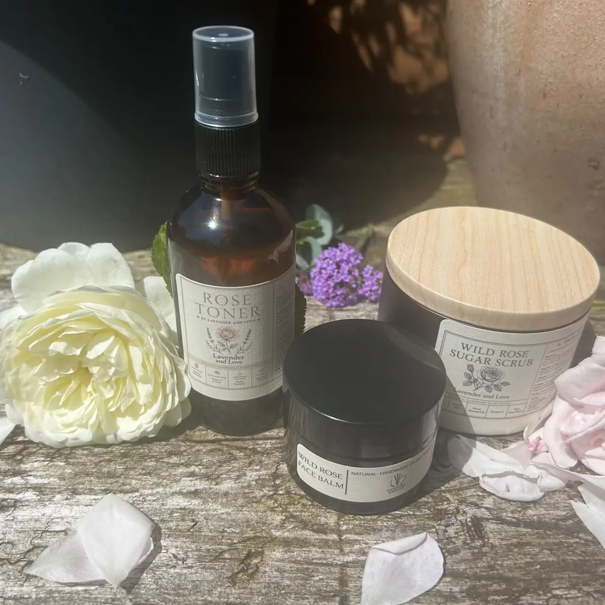 Rose Toner, Wild Rose Face Balm and Wild Rose Sugar Scrub among garden roses and petals