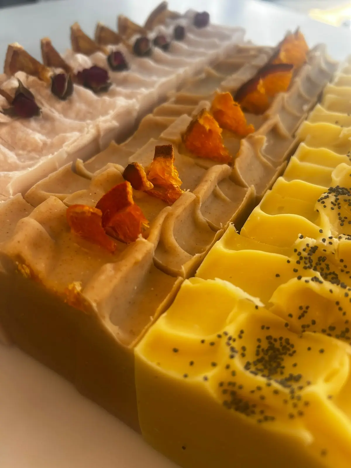 Freshly made soap loaves topped with dried orange, rosebuds and poppy seeds