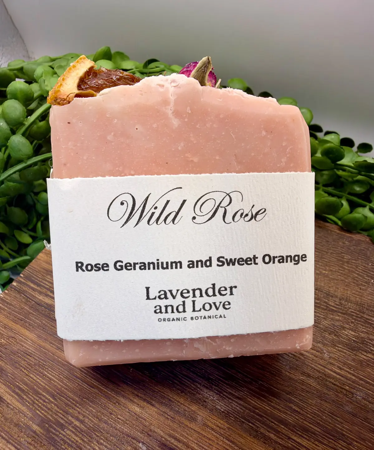 A pink Wild Rose soap with rose geranium and sweet orange, topped with a rosebud and dried orange
